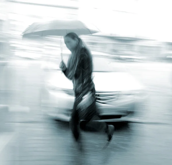 Vrouw lopend onderaan de straat in een regenachtige dag — Stockfoto