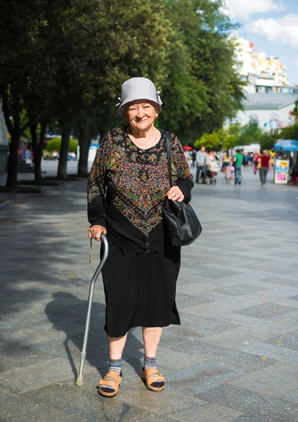 Oude vrouw lopen met een stok — Stockfoto