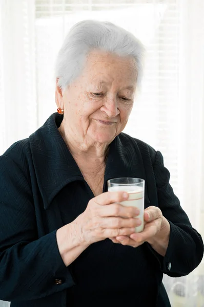 Mulher velha segurando um leite de vidro — Fotografia de Stock