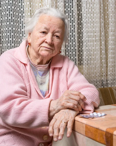 Vieja mujer triste sosteniendo pastillas — Foto de Stock