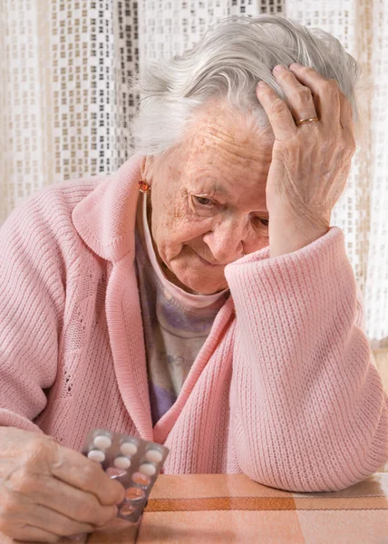Vieja mujer triste sosteniendo pastillas — Foto de Stock