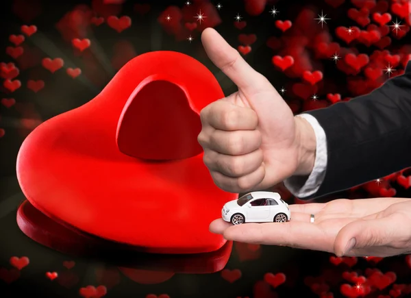 Businessman in black suit holding two small car model — Stock Photo, Image