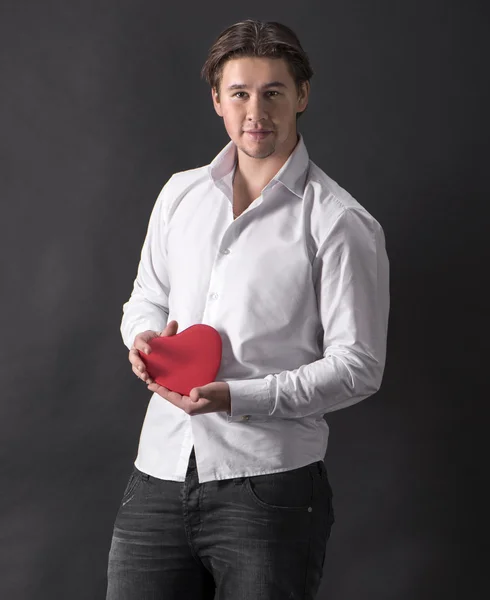 Jovem homem bonito segurando coração vermelho — Fotografia de Stock