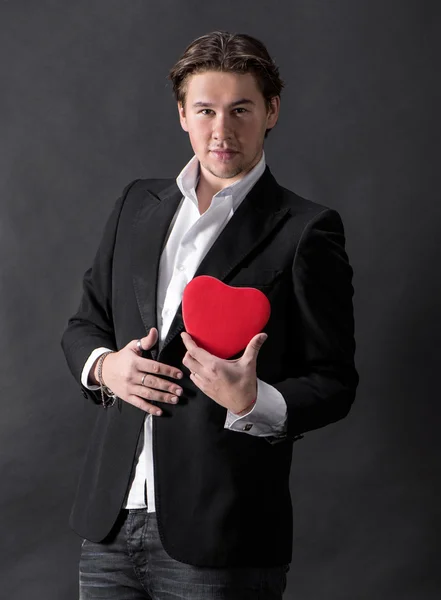 Młody przystojny mężczyzna trzyma czerwone serce — Zdjęcie stockowe