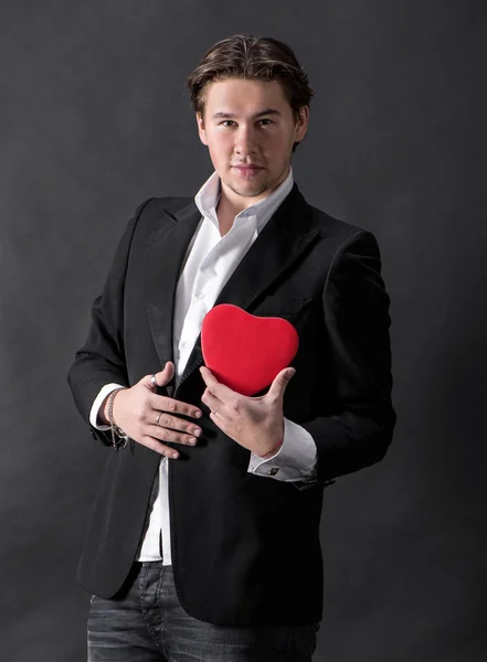 Joven hombre guapo sosteniendo el corazón rojo — Foto de Stock