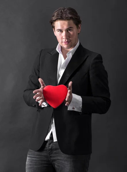 Kırmızı kalp tutan genç yakışıklı adam — Stok fotoğraf