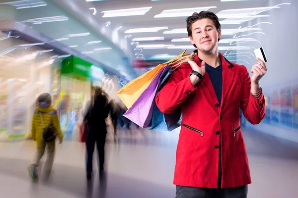 Lachende knappe man met shopping tassen en credit card — Stockfoto