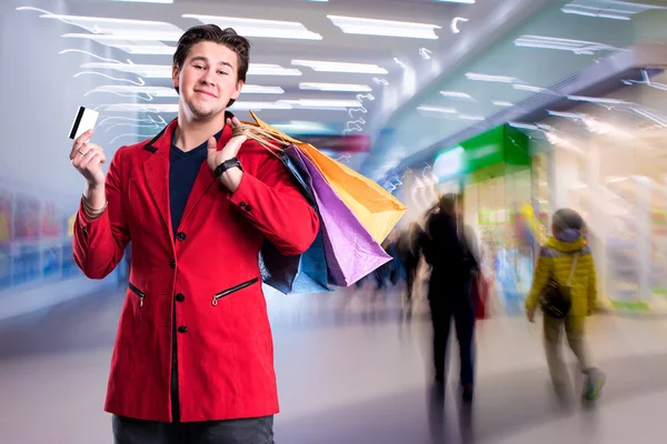 Uomo bello sorridente con borse della spesa e carta di credito — Foto Stock