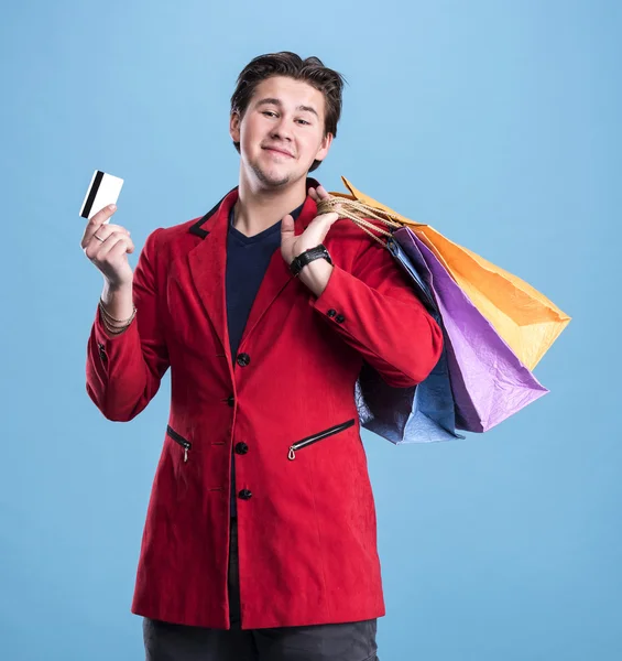 Bel homme souriant avec sacs à provisions et carte de crédit — Photo