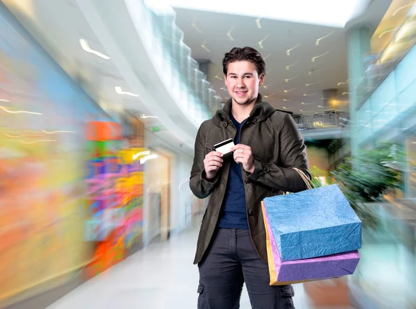 Lachende knappe man met shopping tassen en credit card — Stockfoto