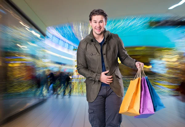 Lachende knappe man met shopping tassen — Stockfoto