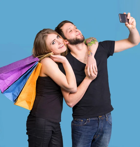 Coppia felice con shopping bags scattare selfie — Foto Stock