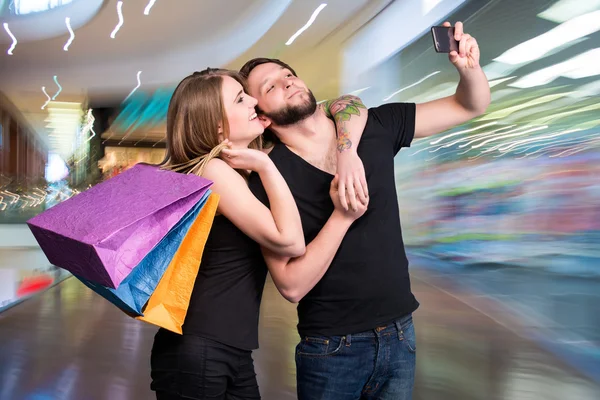 Pareja feliz con bolsas de compras tomando selfie — Foto de Stock