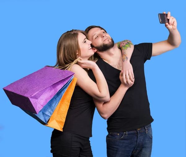 Coppia felice con shopping bags scattare selfie — Foto Stock