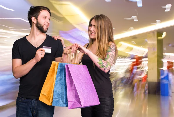 Pareja feliz con bolsas de compras en el mal —  Fotos de Stock