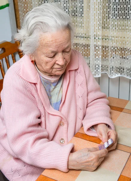 Velha mulher triste segurando pílulas — Fotografia de Stock