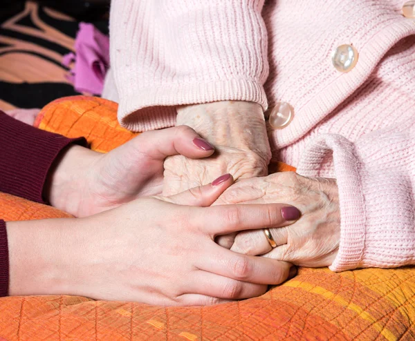 Cuidando las manos sosteniendo las manos de la anciana en casa — Foto de Stock