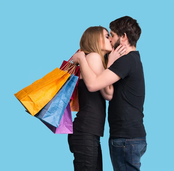 Happy kissing couple with shopping bags — Stock Photo, Image