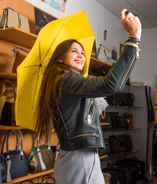 Young woman with yellow umbrella taking selfie — Stock Photo, Image