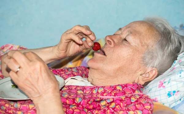 Vieja enferma comiendo fresa —  Fotos de Stock