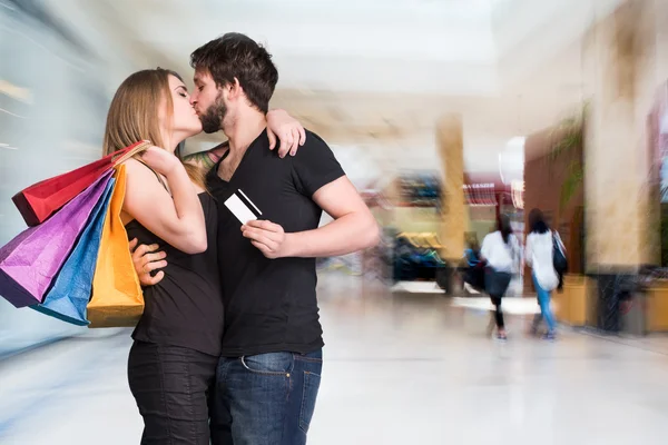 Happy kissing couple with shopping bags at the mall — Stock Photo, Image