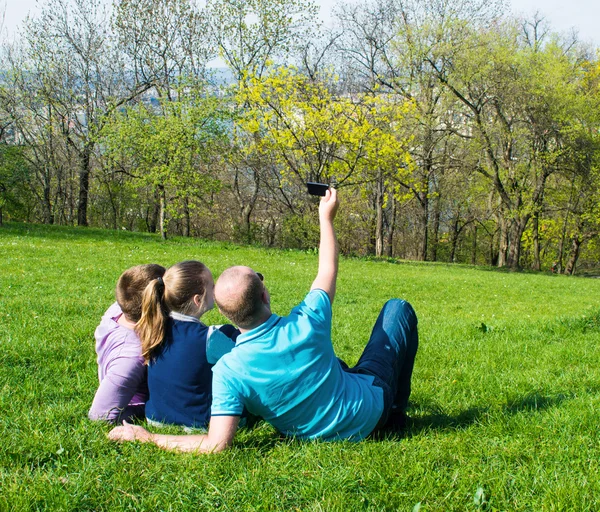 En gruppe smilende venner som tar selfie i parken – stockfoto