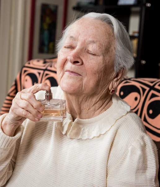 Porträt einer alten Frau mit einer Flasche Parfüm — Stockfoto