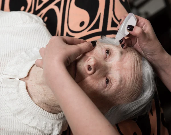 Yaşlı kadına kadın damlayan göz damlası — Stok fotoğraf