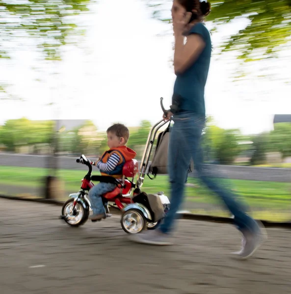 Mutter schiebt kleines Fahrrad mit Sohn — Stockfoto