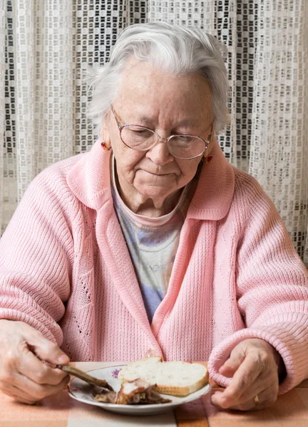 Old sad woman eating at home — Stock Photo, Image