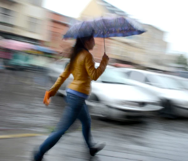 Frau läuft an einem regnerischen Tag die Straße entlang — Stockfoto