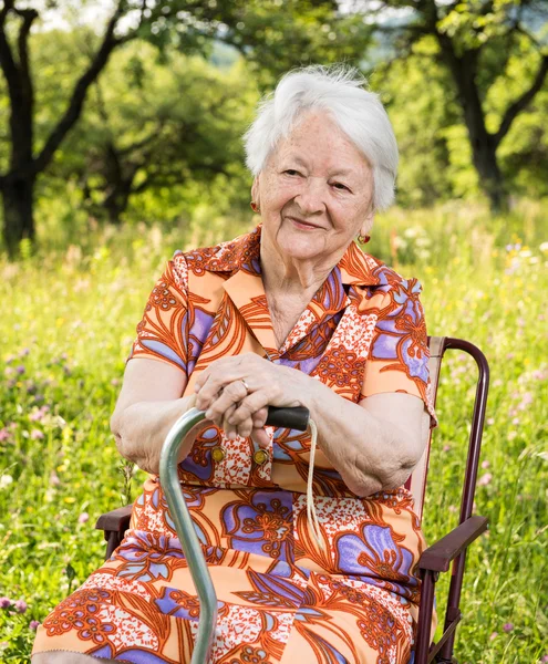 Güzel gülümseyen yaşlı kadın sandalyede oturuyordu — Stok fotoğraf