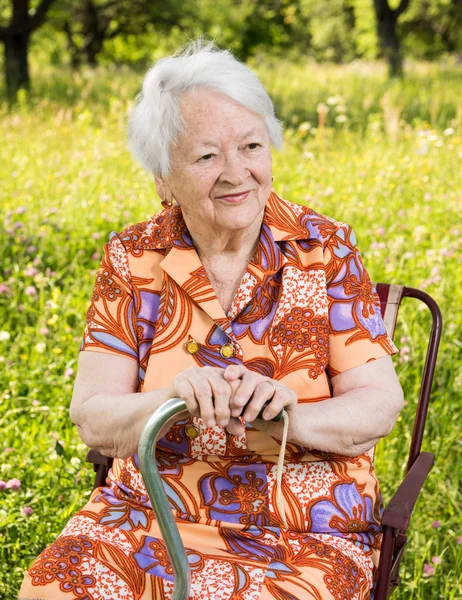 Schöne lächelnde alte Frau auf dem Stuhl sitzend — Stockfoto