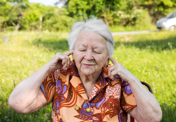 Oude vrouw behandelt haar oren met handen — Stockfoto