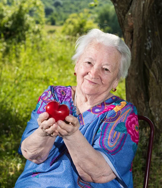 Vieille femme tenant le cœur rouge dans les mains — Photo