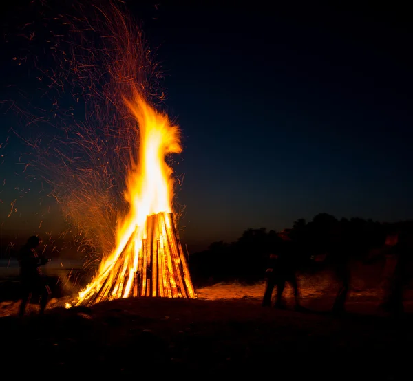 Gente descansando cerca de una gran hoguera al aire libre — Foto de Stock