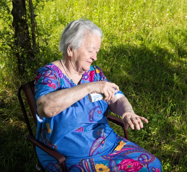 Mulher velha pulverizando repelente de insetos — Fotografia de Stock