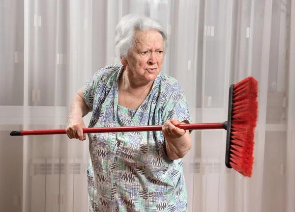 Vecchia donna arrabbiata che minaccia con una scopa — Foto Stock