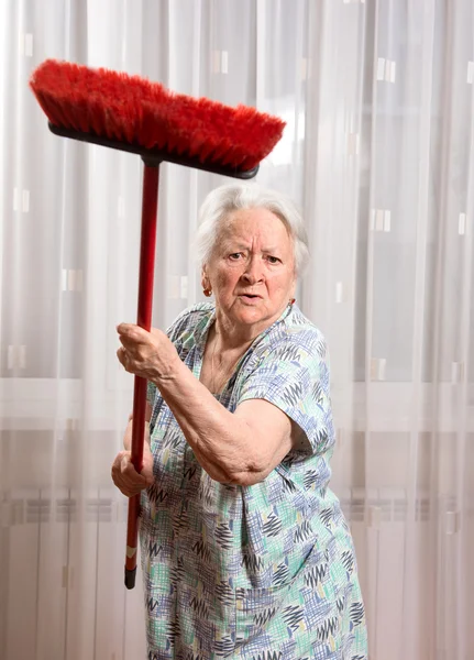 Vecchia donna arrabbiata che minaccia con una scopa — Foto Stock