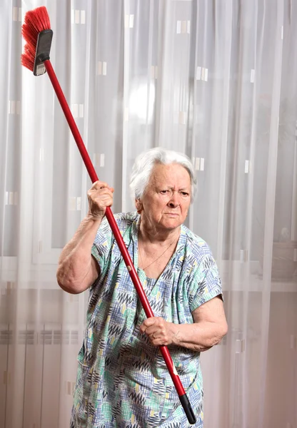 Régi dühös nő egy seprűvel fenyegeti — Stock Fotó