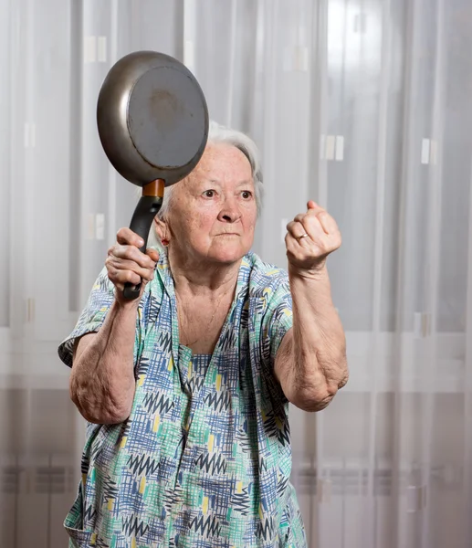 Angry old woman with a pan — Stock Photo, Image