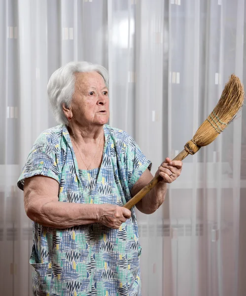 Velha mulher zangada ameaçando com uma vassoura — Fotografia de Stock