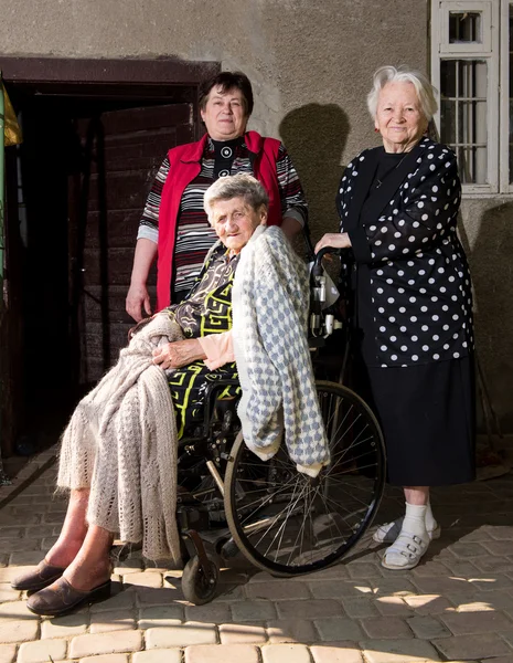 Old woman in wheel chair with family — Stock Photo, Image