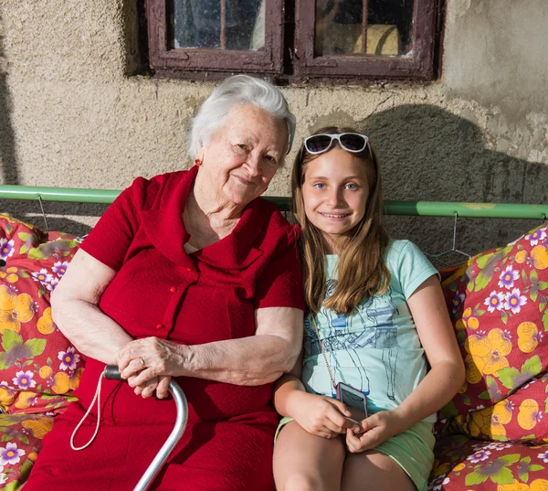 Büyükanne ve torunu bankta oturan — Stok fotoğraf