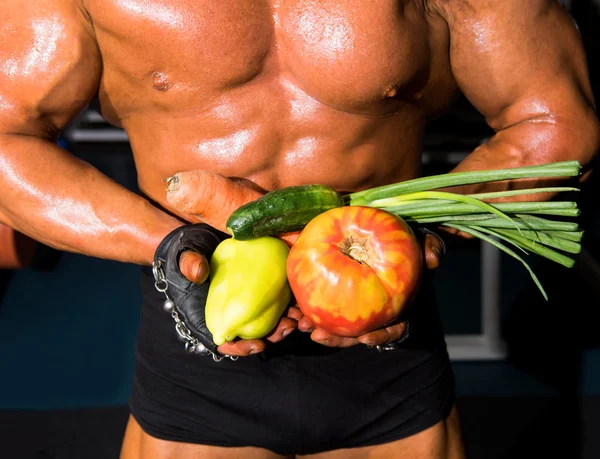 Bodybuilder holding vegetables — Stock Photo, Image