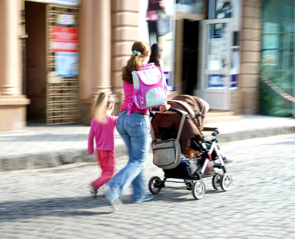 Familia joven con un niño pequeño y un cochecito caminando por la calle —  Fotos de Stock