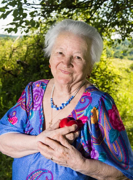 Old woman holding red heart — Stock Photo, Image