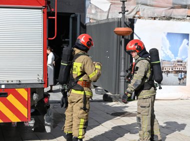 UZHOROD, UKRAINE - 30 Eylül 2025: Güvenlik ekipmanlı itfaiyeciler gündüz saatlerinde halka açık bir yerde itfaiye aracının yanında göreve hazırlanıyorlar