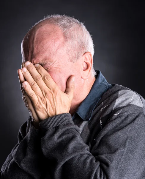 Oudere man met gezicht gesloten met de hand — Stockfoto