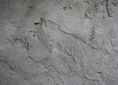 Değişik dokular, tanecikli detaylar ve ince kusurlar içeren pürüzlü, düzensiz, gri beton bir yüzeyin yakın çekim, tam kare görüntüsü.